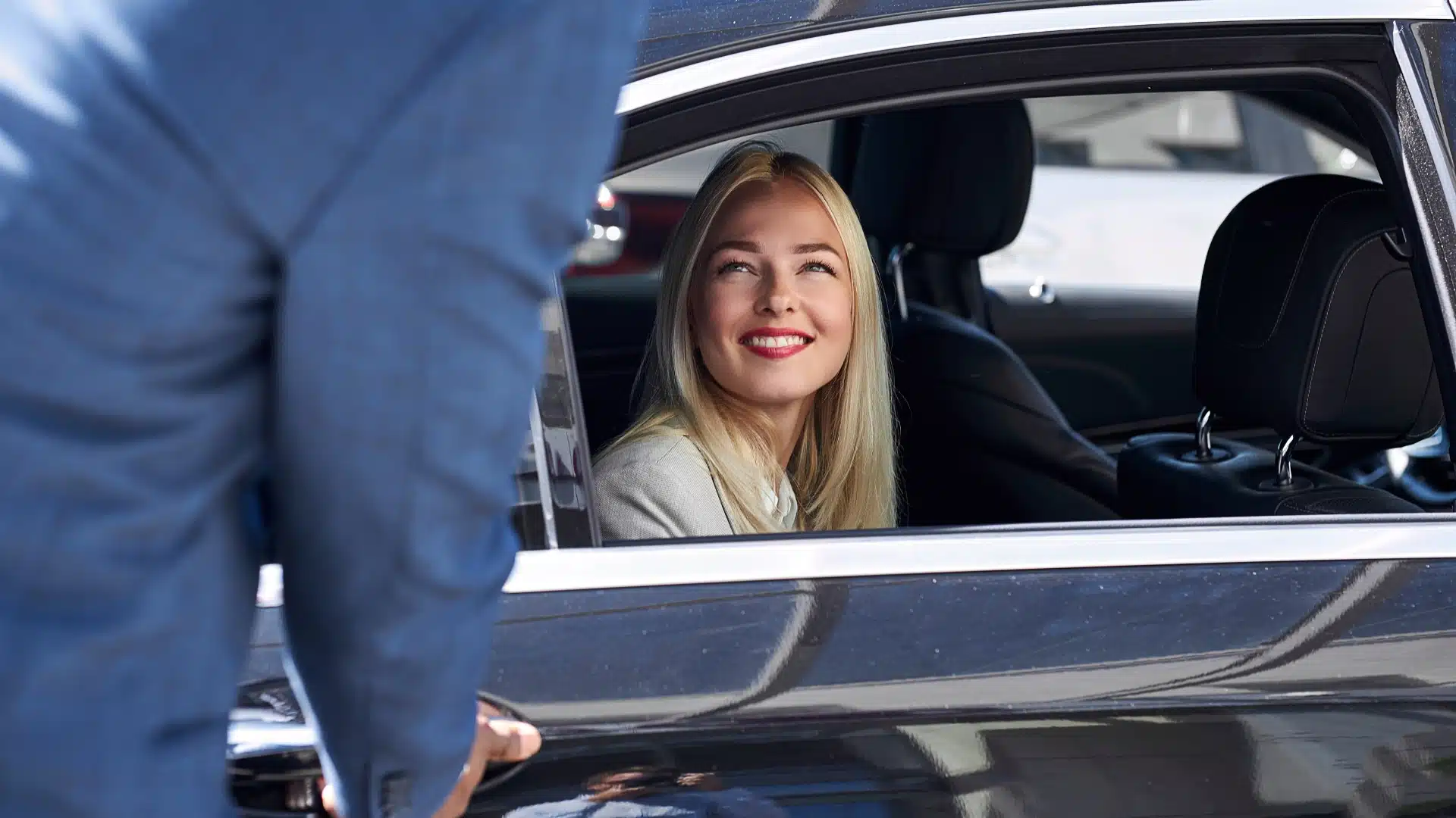Blije jonge vrouw lacht uit het raam van een taxi – snel een taxi met Panorama Taxi.