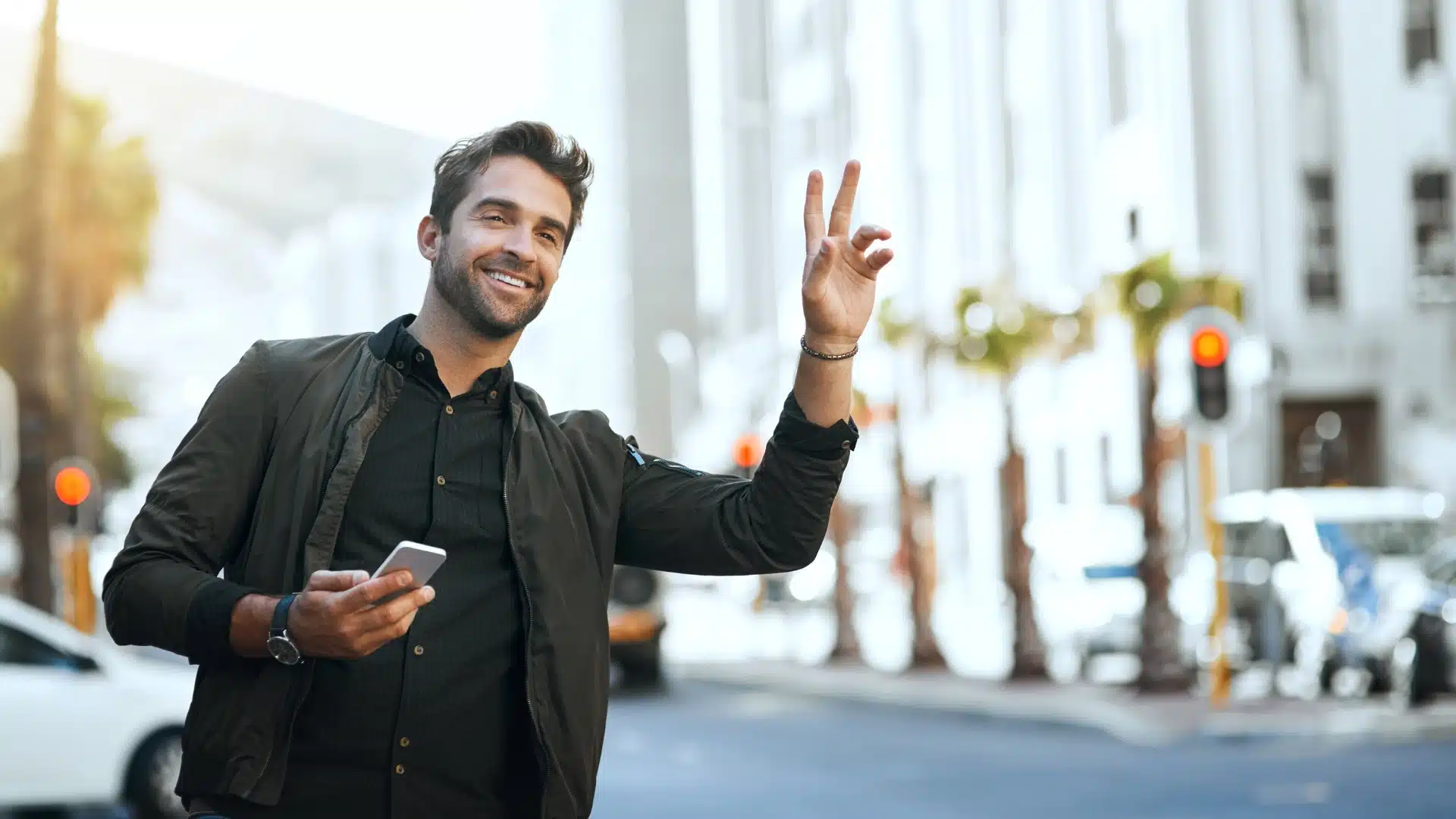 Lachende man houdt zijn telefoon vast en zwaait naar een taxi – snel een taxi met Panorama Taxi.