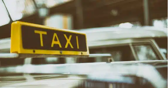 Snel een taxi vanaf Schiphol – Gele taxi met bord klaar voor luchthavenvervoer